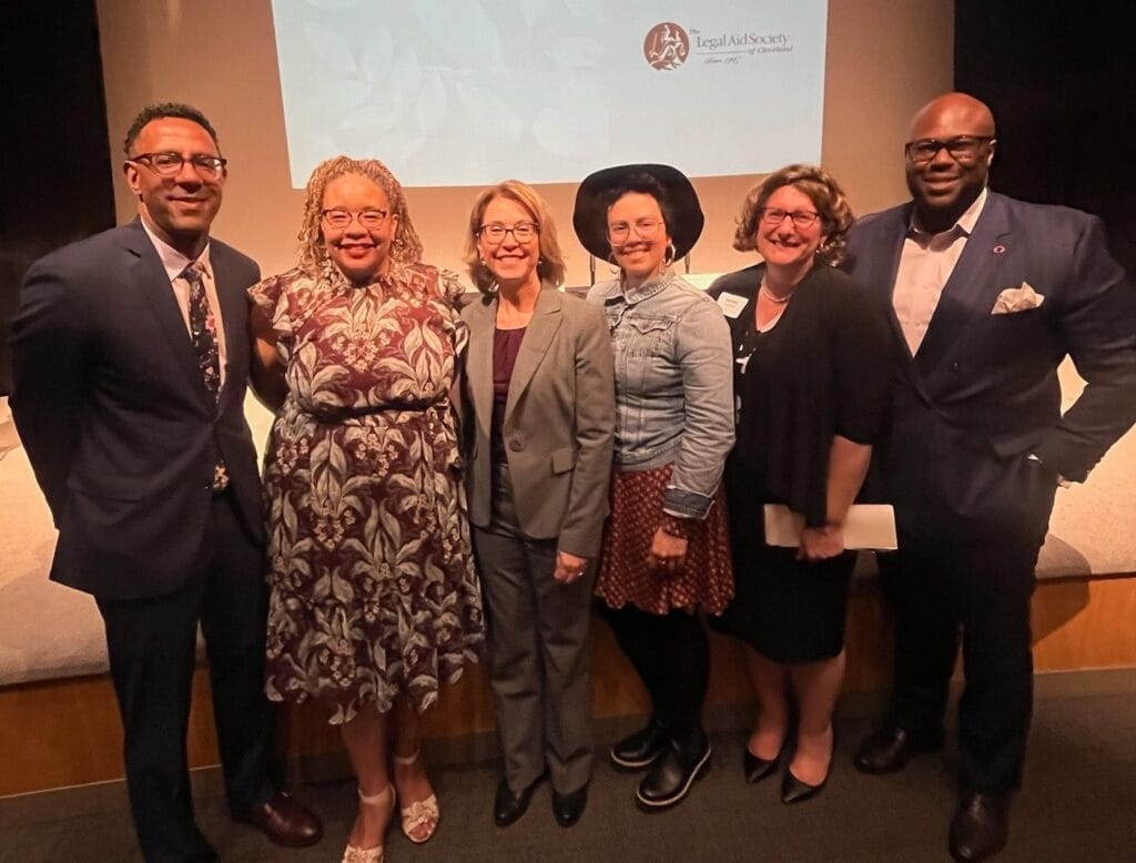 A group of six people stand together at an event.